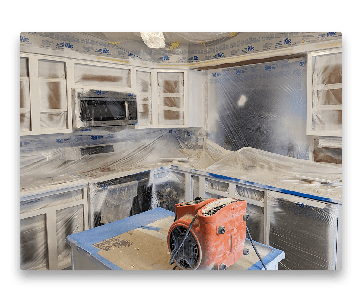 An image depicting a kitchen with masking in preparation for kitchen cabinet painting.